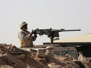 A Saudi soldier sits on top of an armor vehicle as he aims his weapons, on the border with Yemen, at a military point in Najran, Saudi Arabia, Tuesday, April 21, 2015. (AP Photo/Hasan Jamali)